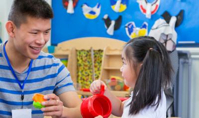 Male educator smiling at preschool student